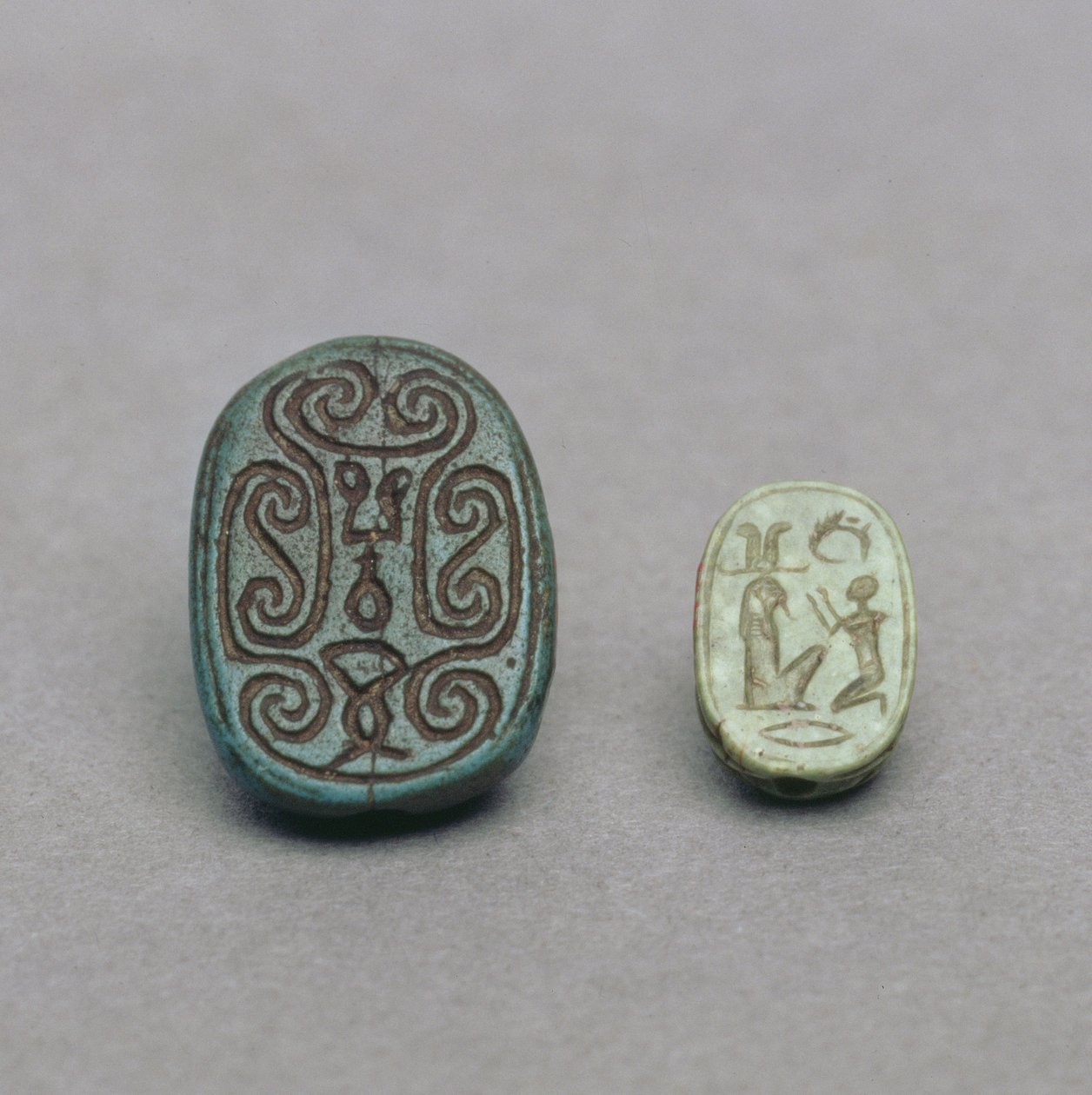 (L-R) Egyptský fajánsový amulet skarabea, 2. přechodné období, 13.-17. dynastie, cca 1650 př. Kr.; amulet skarabea ze zeleného živce, pozdní období, 26. dynastie, cca 600 př.n.l. od Egyptian
