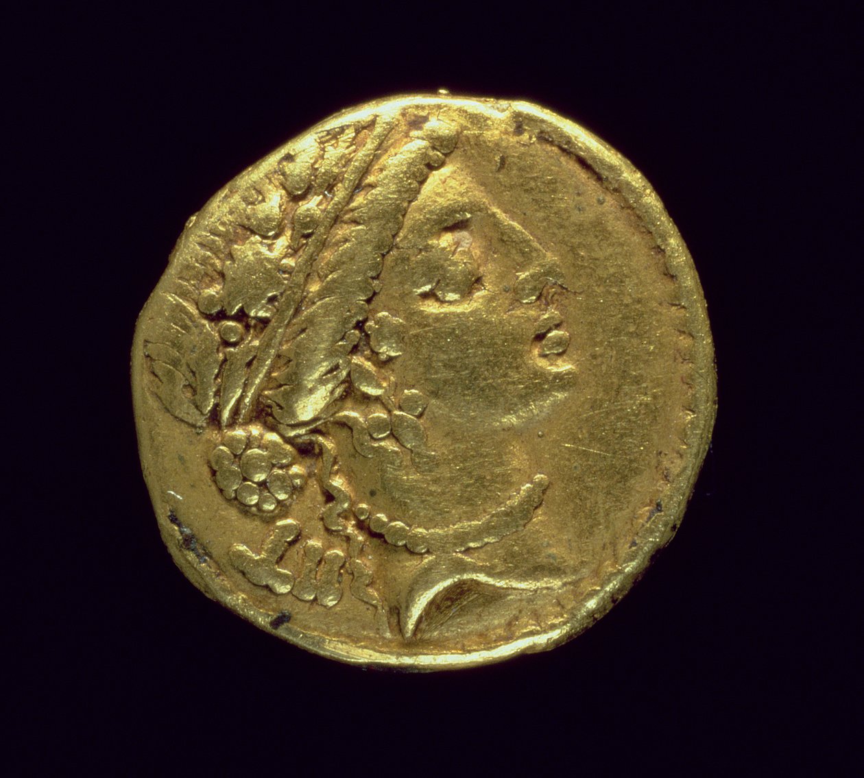 Aureus (avers) ražený Juliem Caesarem (110-44 př. n. l.) zobrazující ženskou hlavu napravo s dubovým věncem a diadémem (zlato) od Roman